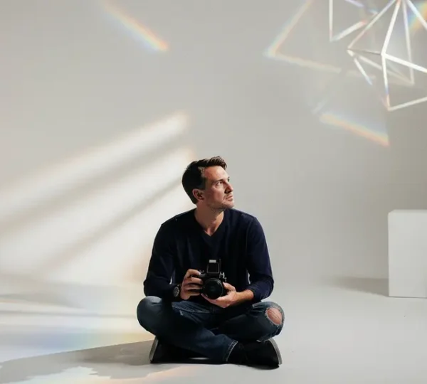 Artist photographer contemplating portfolio amid creative tools and symbolic elements representing vision breakthrough