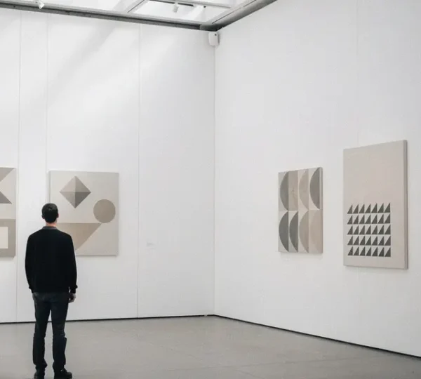 Curator standing in contemporary gallery space arranging conceptual artwork displays with dramatic lighting