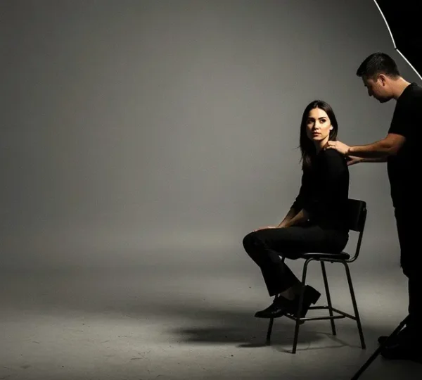 Professional photographer adjusting studio lighting for dramatic portrait with visible light ratios