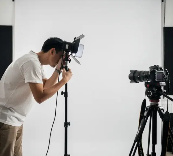 Professional photographer working in a compact home studio with strategic lighting setup and minimal equipment