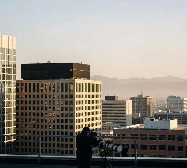 Photographer capturing compressed urban layers with telephoto lens showing distant buildings stacked behind foreground architecture